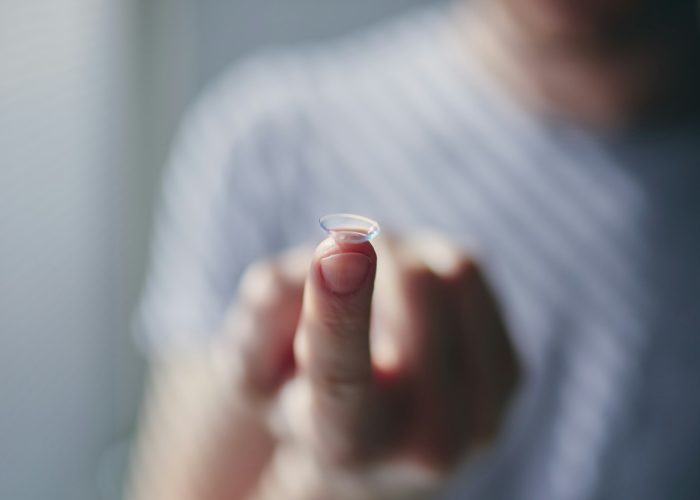 Close-up of contact lens on finger of young man